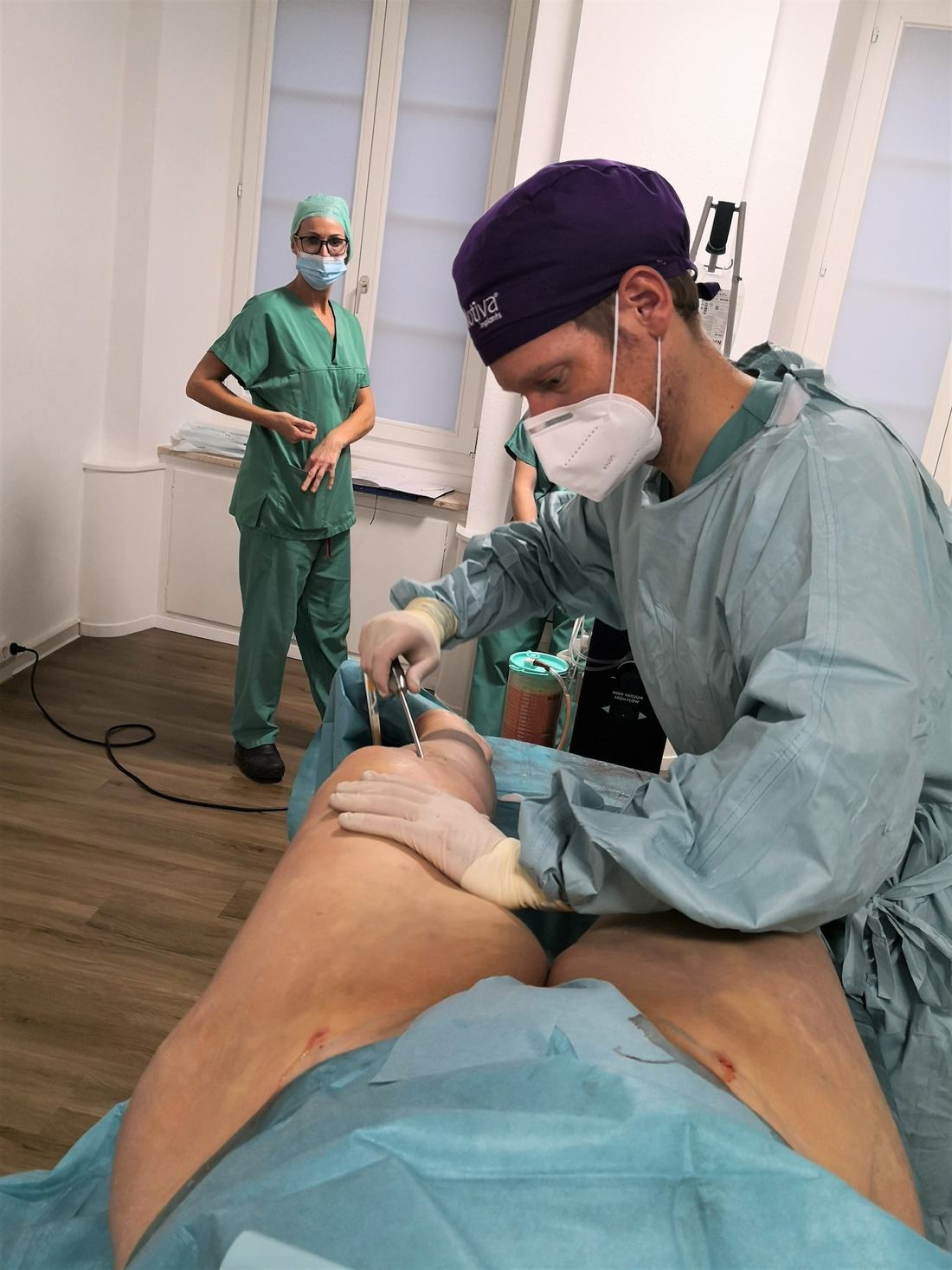 Arzt bei der Liposuktion am Bein einer Patientin
