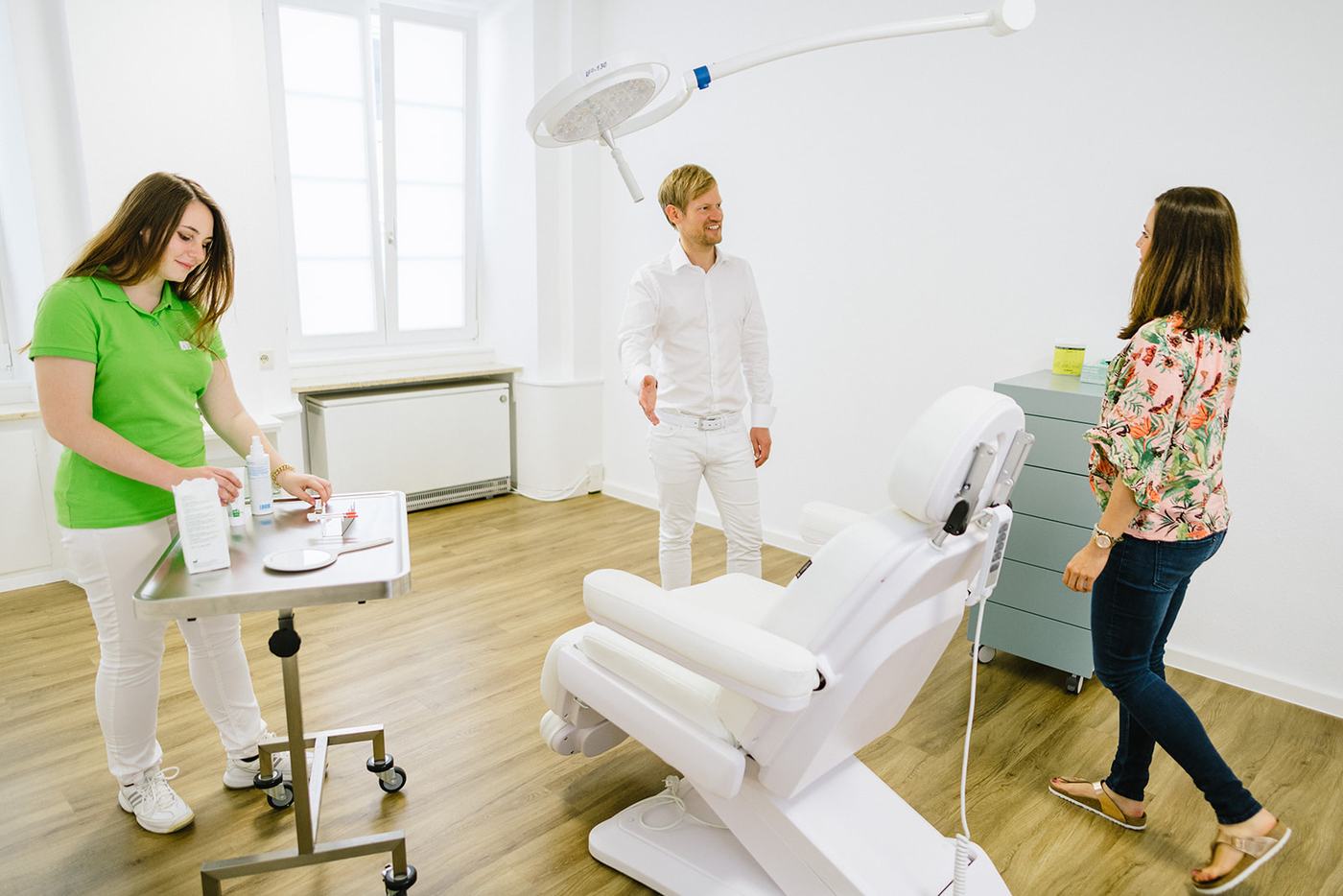 Behandlungsraum der Praxis mit Ärztin, Arzt und Patientin